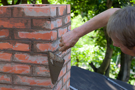Technician applying stucco to chimney